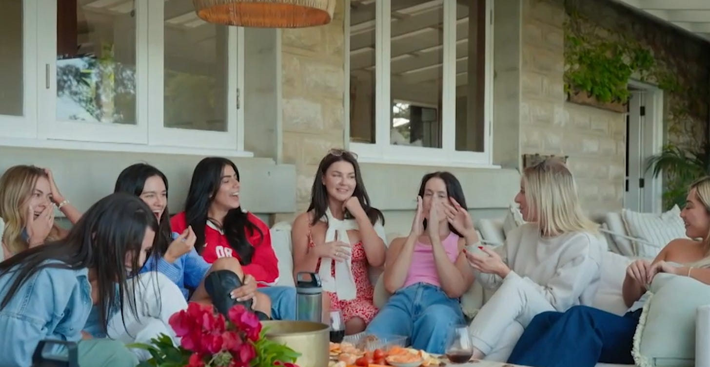 The MAFS 2025 brides laugh and react on an outdoor couch, with drinks and snacks in front of them.