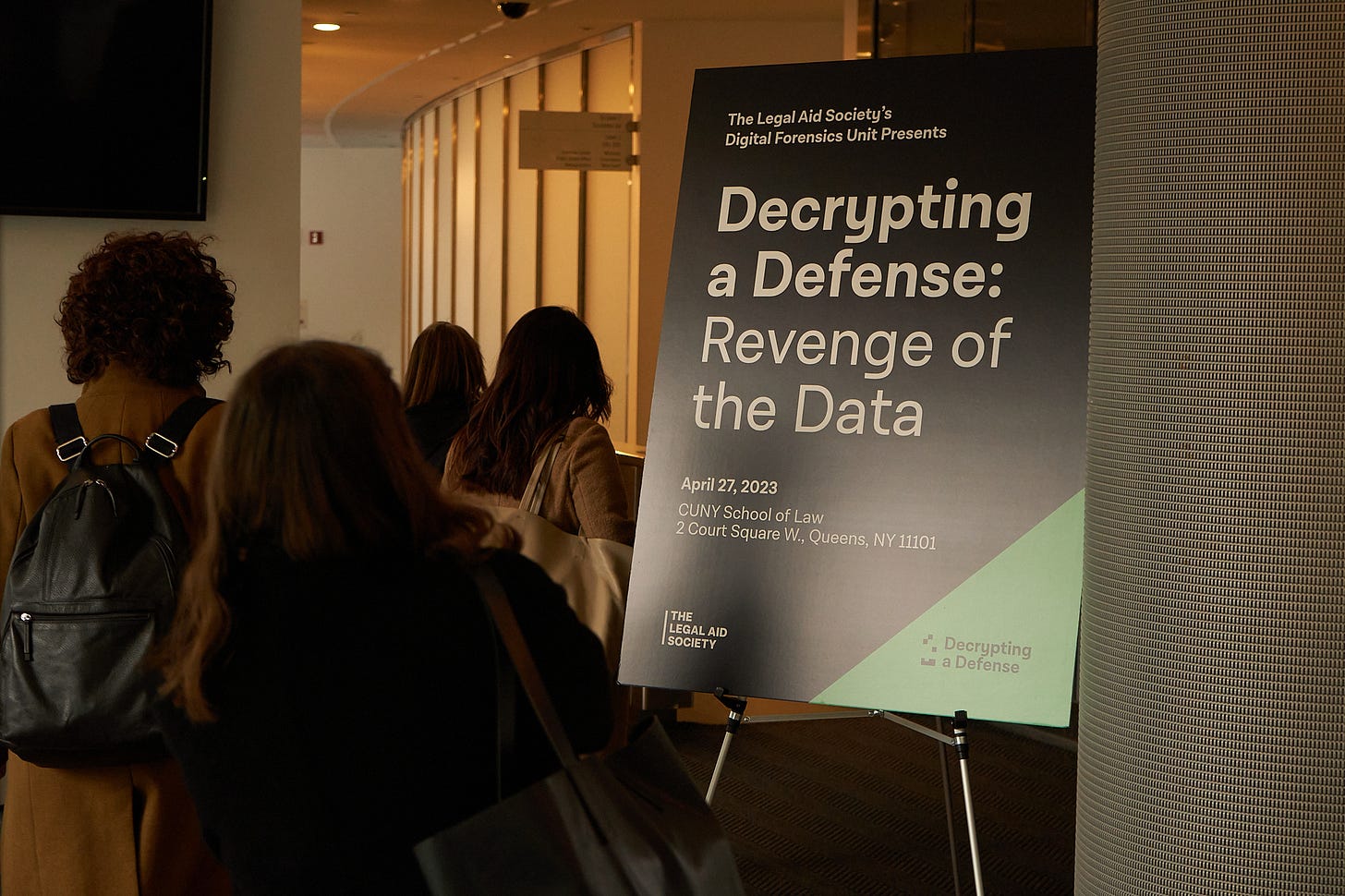 Attendees walking past the Decrypting a Defense: Revenge of the Data welcome sign.