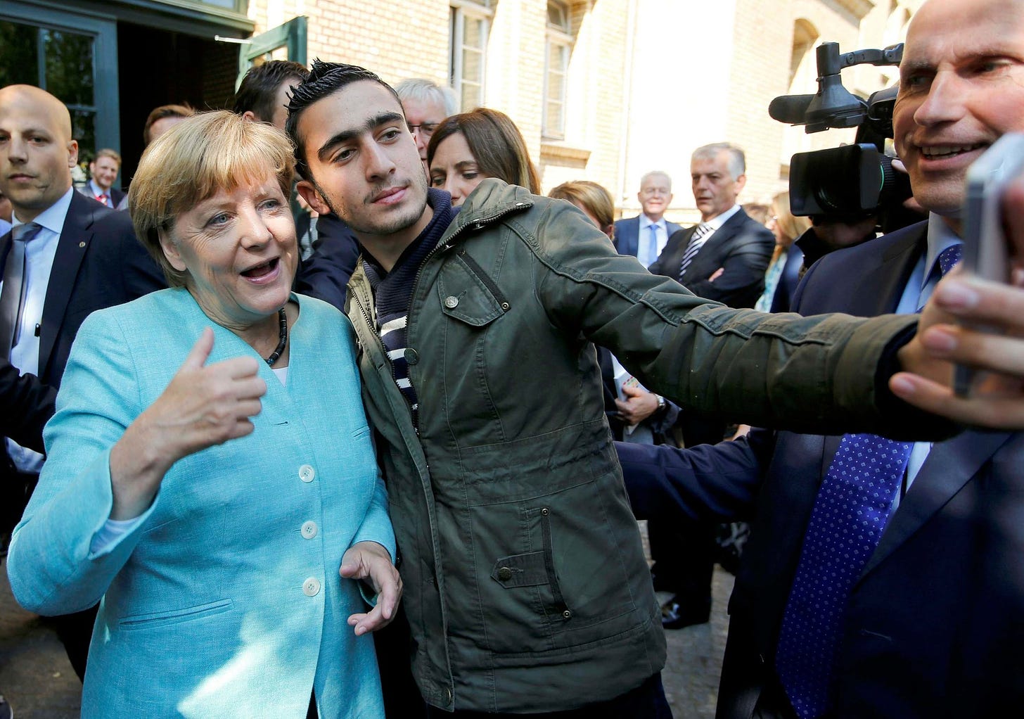 Angela Merkel, who invited the third world into Europe in 2015, poses with a migrant