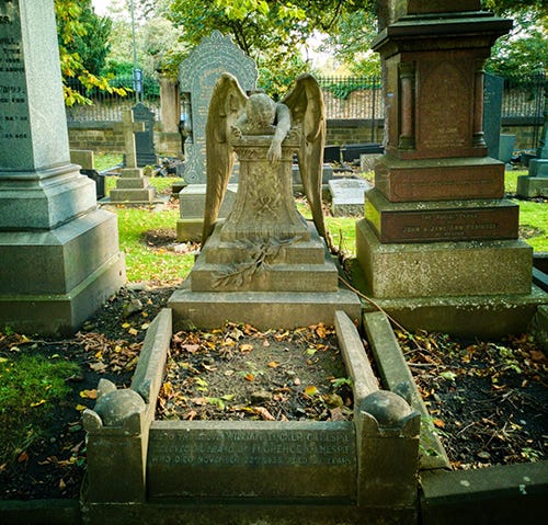 An image of an angel leaning forwards across a tomb, her face pressed down onto the stone.