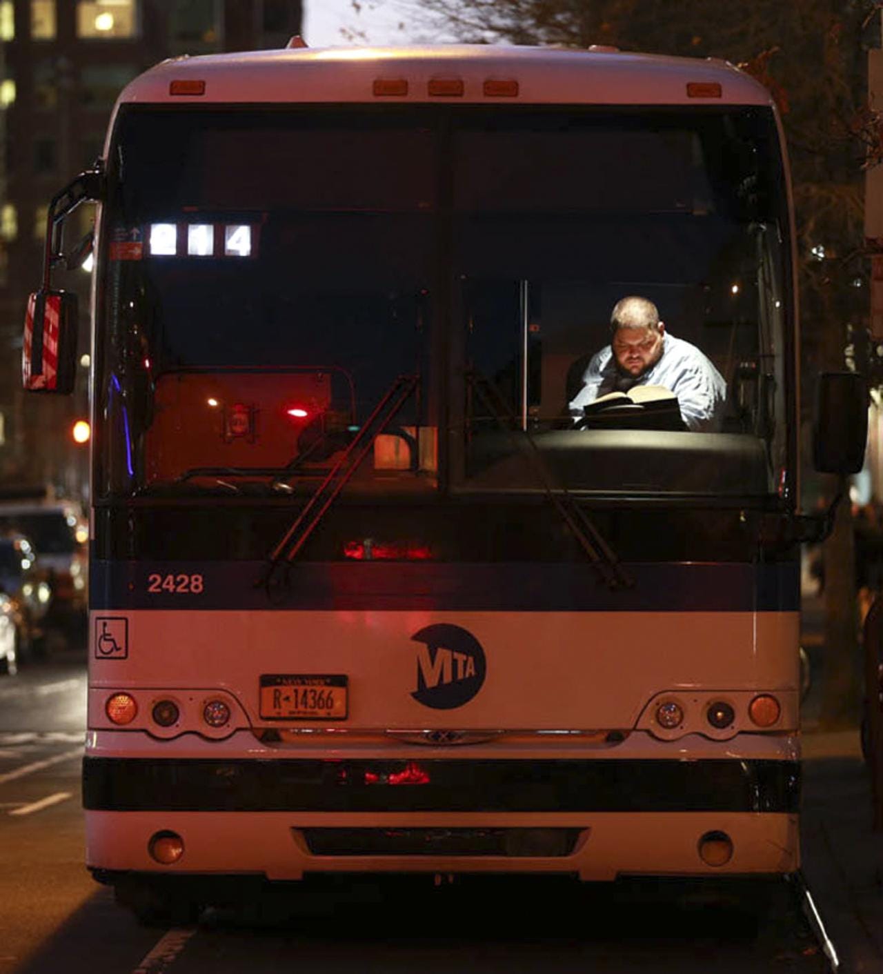 A New York City bus driver reads a book during a break on Greenwich and Warren Street in Tribeca.