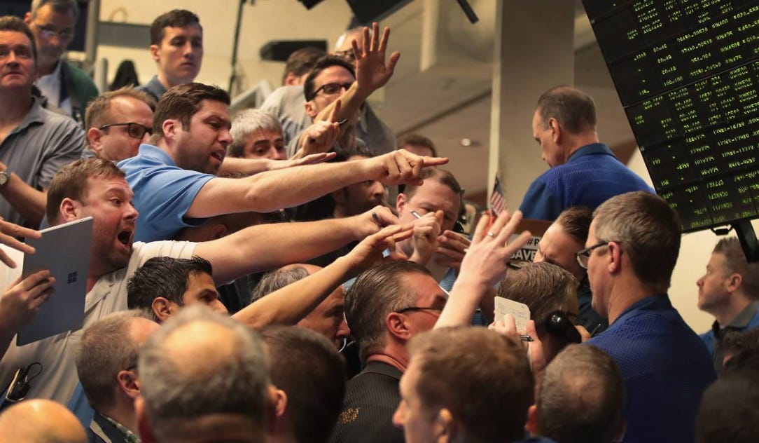 Chaotic scene on a stock trading floor with traders gesturing and shouting, many pointing or raising hands. A digital display with financial data is visible in the background.