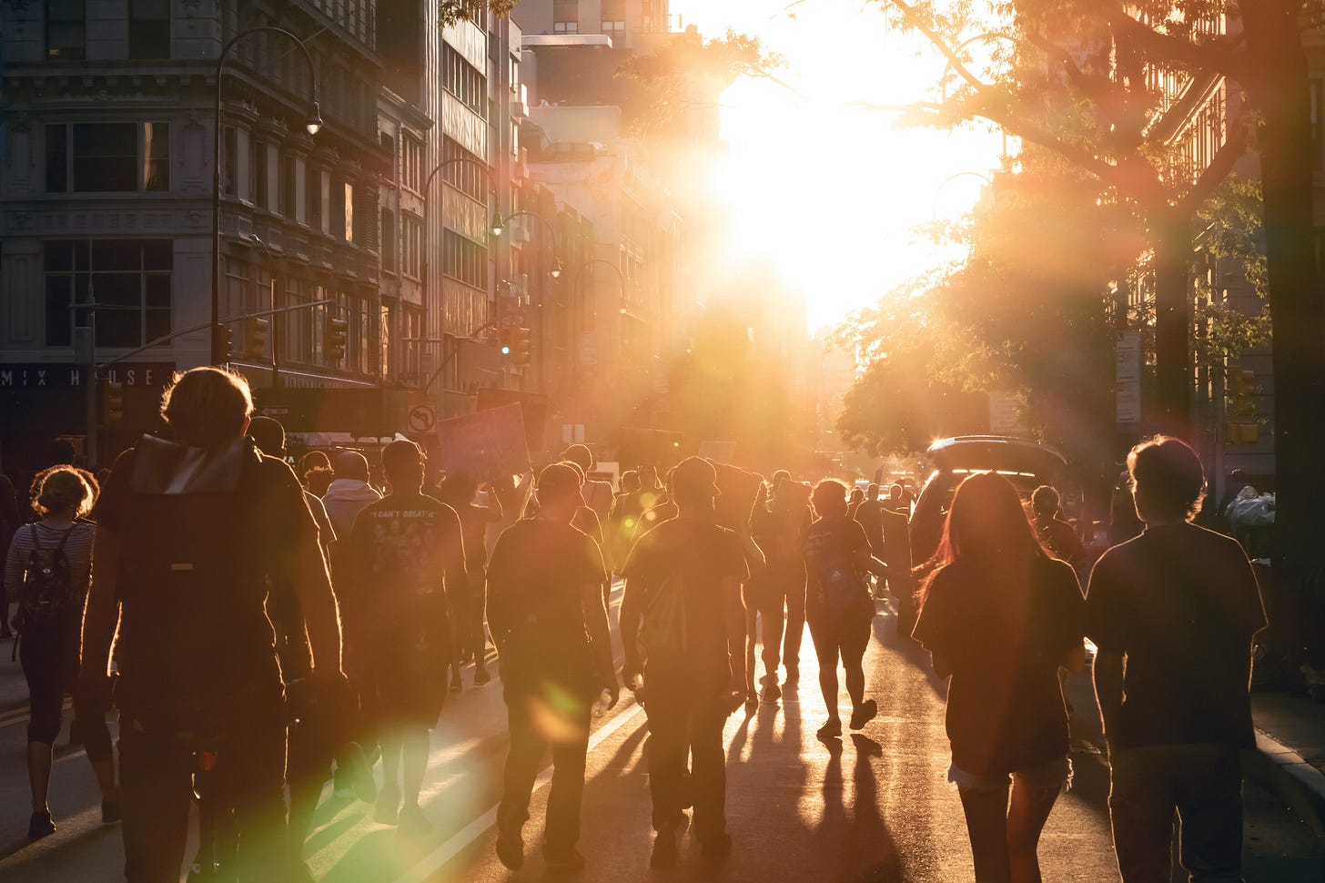 Protestors walk into the light of sunset on a city street.