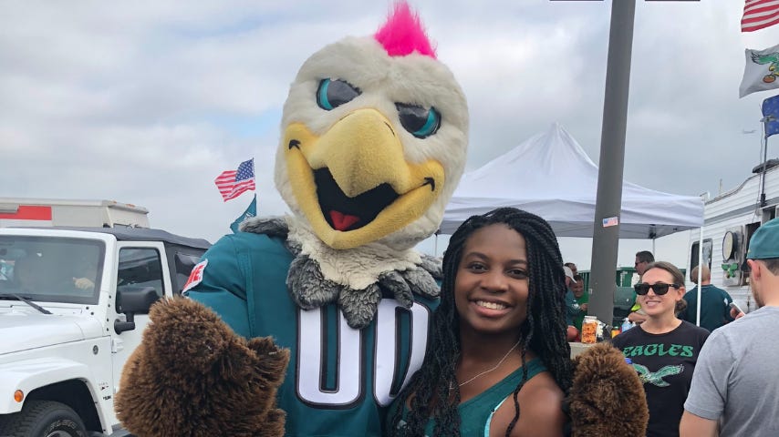 Monique Boskett, the article's subject, posing next to Swoop the Eagle, mascot for the Philadelphia Eagles