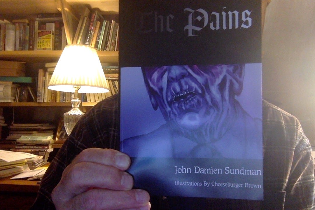 Photo of me in my office holding a copy of The Pains, which obscures my face. The words 'The Pains' are set in a faux medieval typeface above a blue-tinged nightmarish portrait of the lower half of what is clearly Ronald Reagan's face.