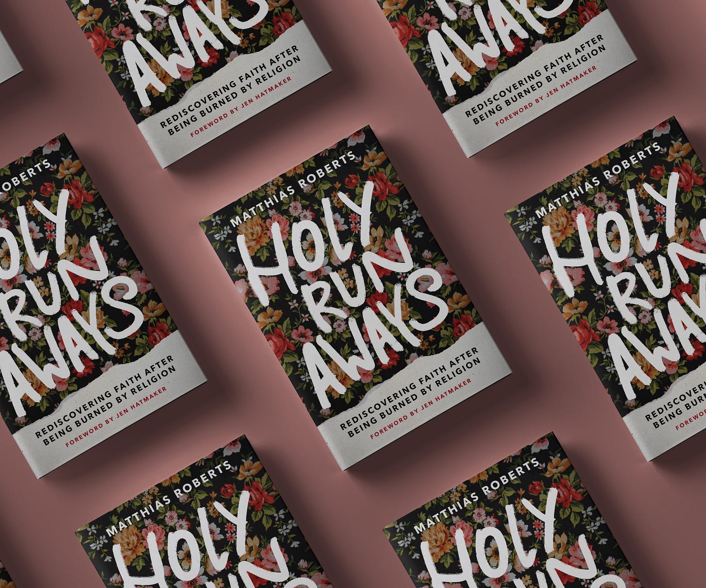 Several copies of Holy Runaways arranged neatly on a dusty pink background. The book cover has dark floral print with the words "Holy Runaways" in bold white handwriting.