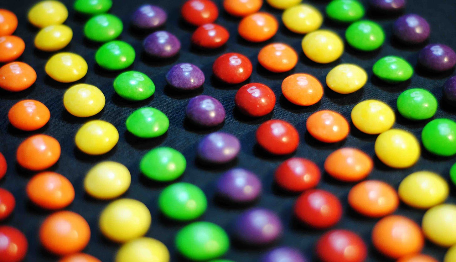 Rainbow skittles lined up on a black background