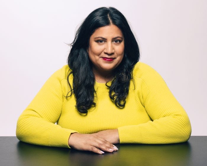 Samhita Mukhopadhyay wearing a yellow sweater smiling into camera