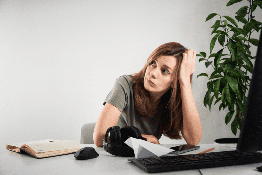 young woman procrastinating at desk looking away from screen