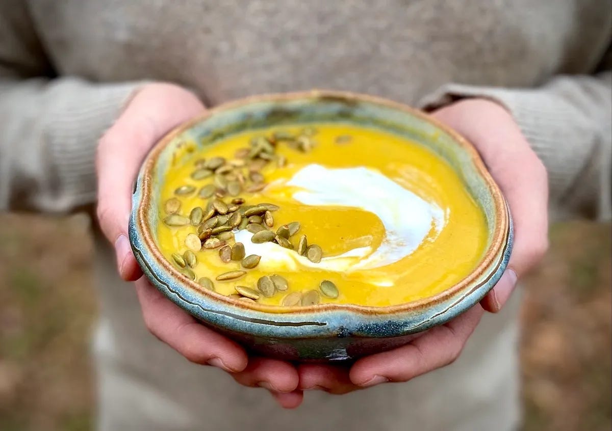 Someone holding a bowl of butternut squash soup.