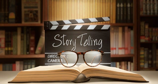 A pair of glasses resting on an open book in front of a movie style clapperboard that has the word Storytelling written on it.