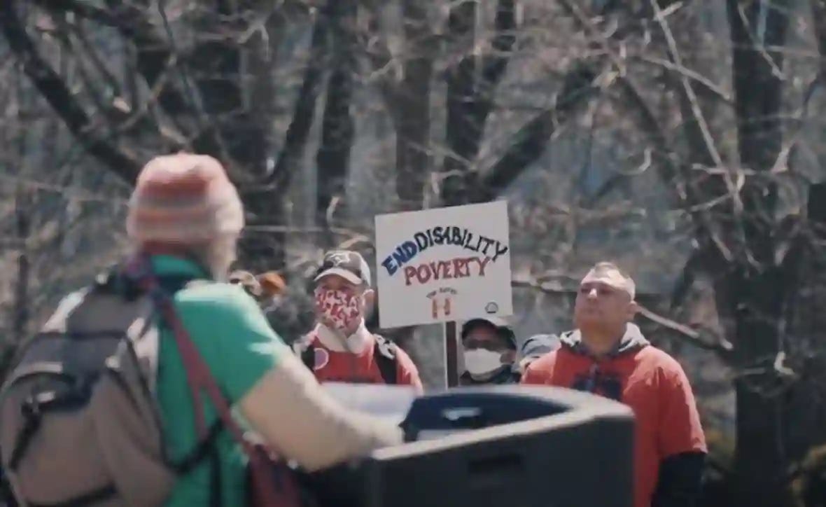 Protesters hold a sign at a demonstration to end disability poverty and raise social assistance rates in April 2022 at Queen's Park in Toronto. A rally is scheduled Thursday for disability advocates in front of Finance Minister Chrystia Freeland's office to push for improvements to the Canada Disability Benefit.