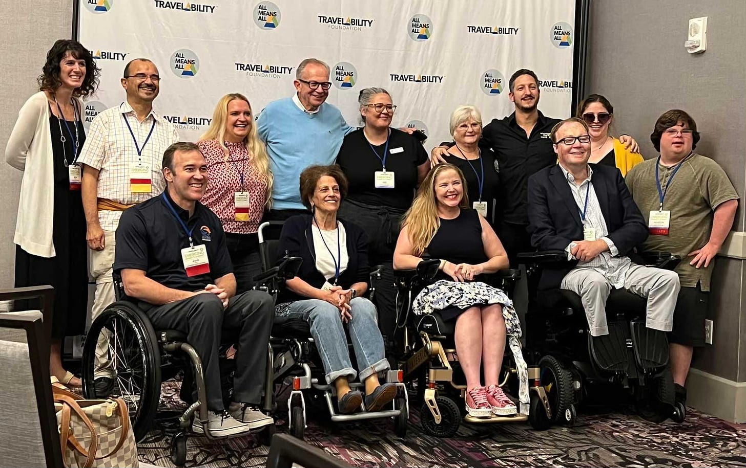 John pictured with multiple wheelchair users at TravelAbility Summit.