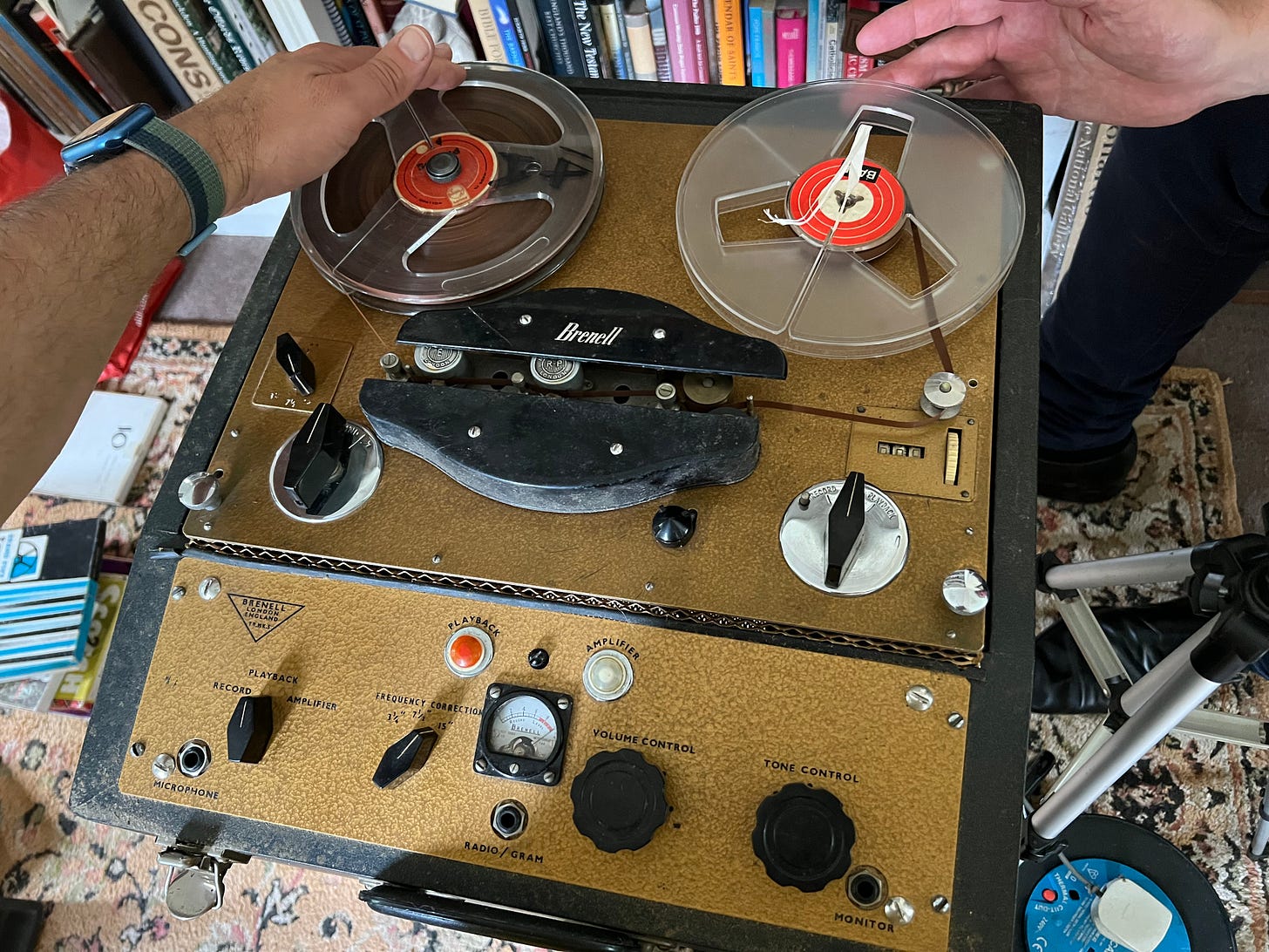 A photo of a reel to reel tape recorder with people manually winding tape
