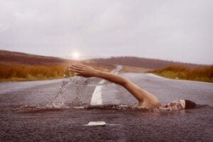 Dream-like image of a person swimming acorss an asphalt road