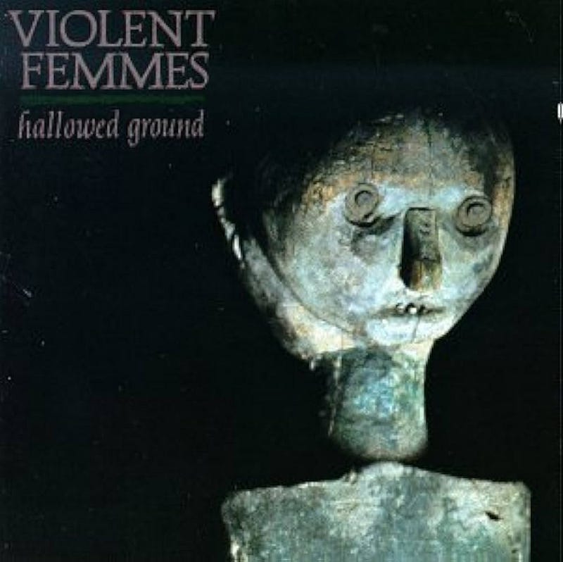 The face & neck of a small sculpture spotlit against a black background. Band name and record title are in block letters in the upper left corner of the cover.