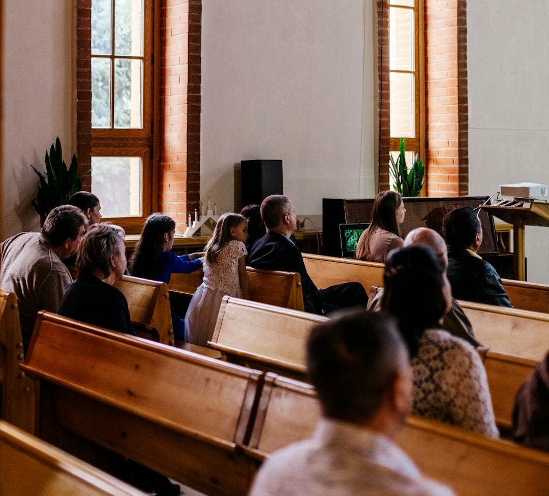 a group of people sitting in pews in a church a group of people sitting in pews in a church