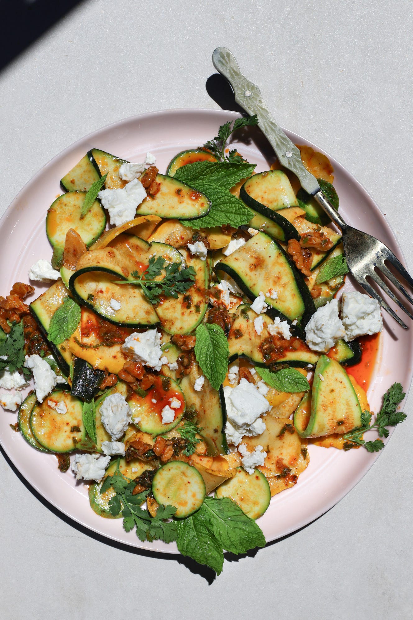 Plate of shaved summer squash with harissa-walnut dressing, feta, and mint