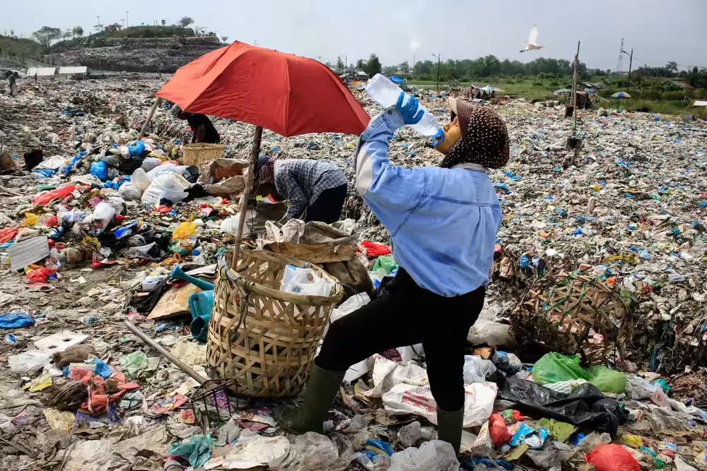 Seorang ibu sedang minum di tengah kegiatan mengumpul sampah plastik untuk dijual kembali di Medan, Sumatera Utara, Indonesia Maret 2024