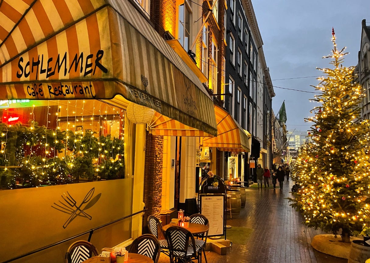 street scene: dark, Christmas lights, rain, and on the left Cafe Schlemmer