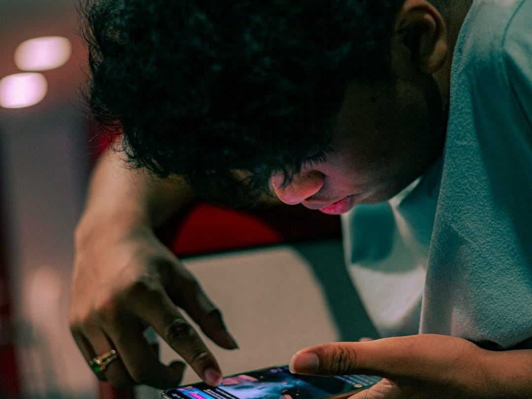 A man sitting down looking at a cell phone A man sitting down looking at a cell phone