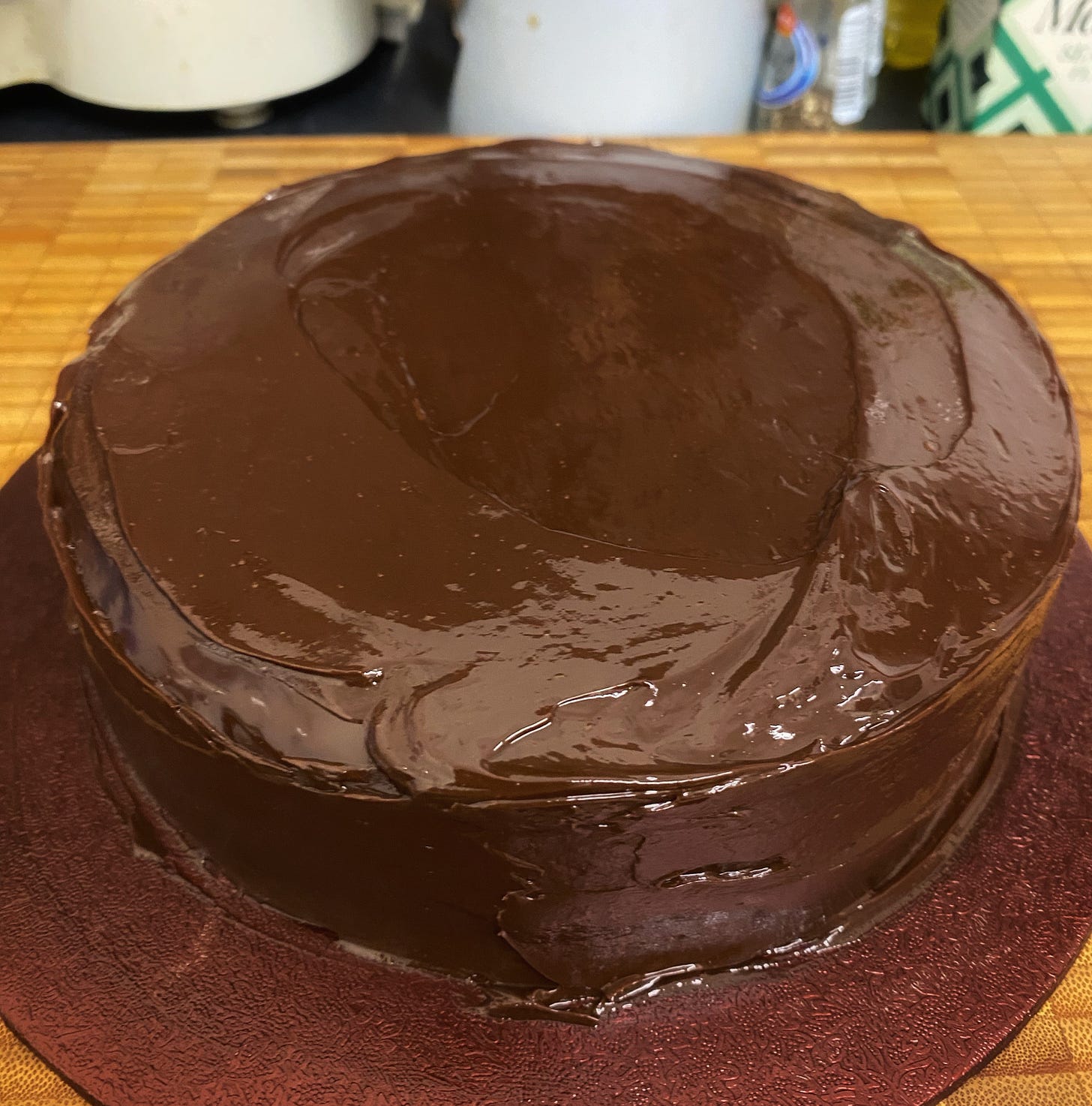 A shiny, ganache-covered chocolate cake that still looks quite messy around the edges