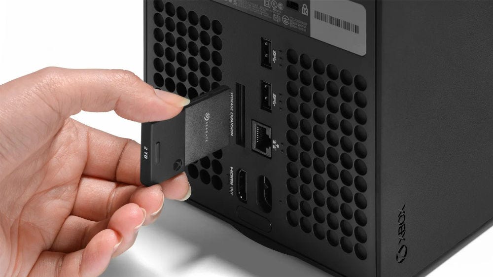 A hand plugging in an Xbox storage card into the back of an Xbox Series X