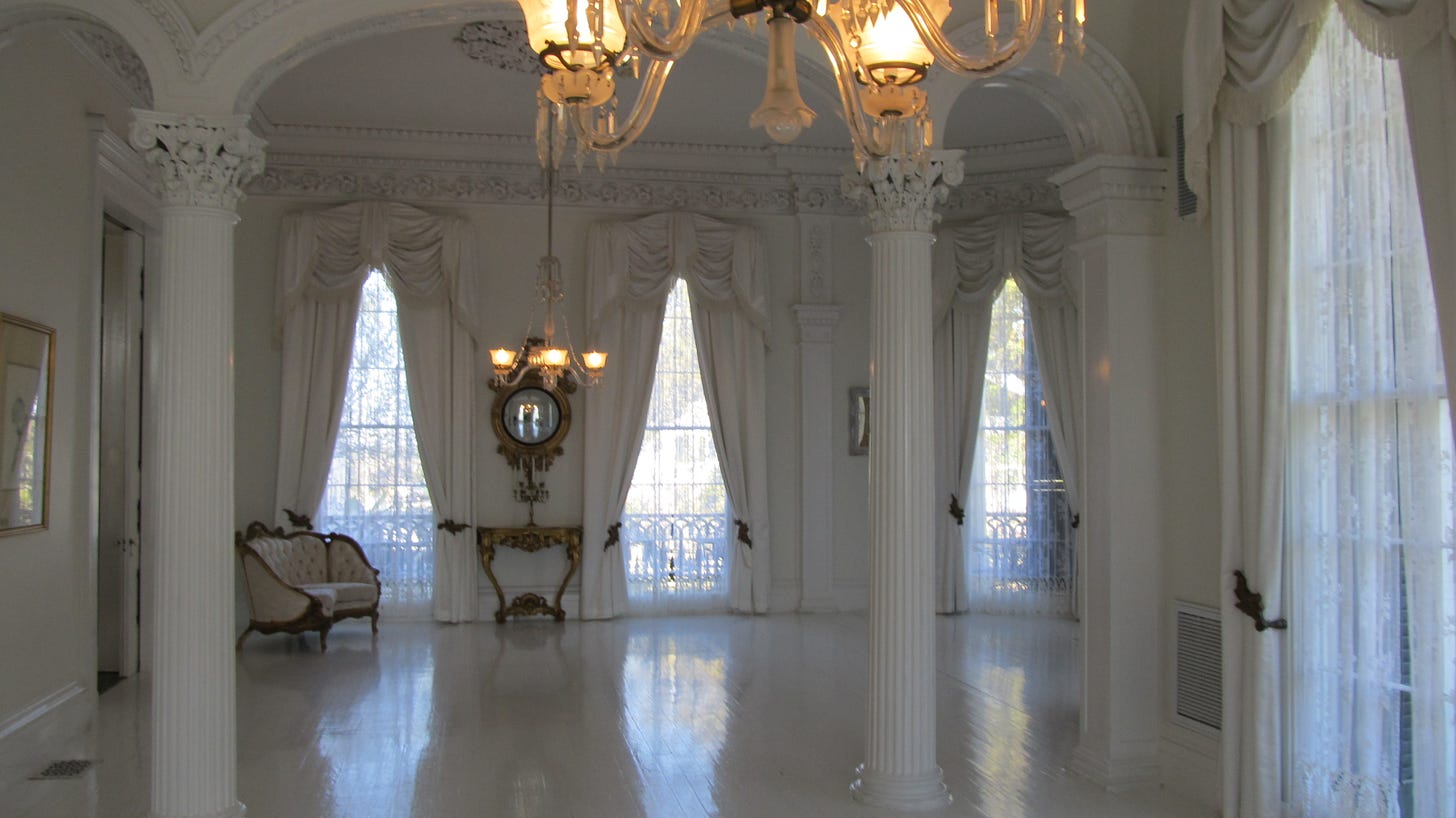 The white ballroom at Nottoway showing white pillars, white floor, white draperies and walls.