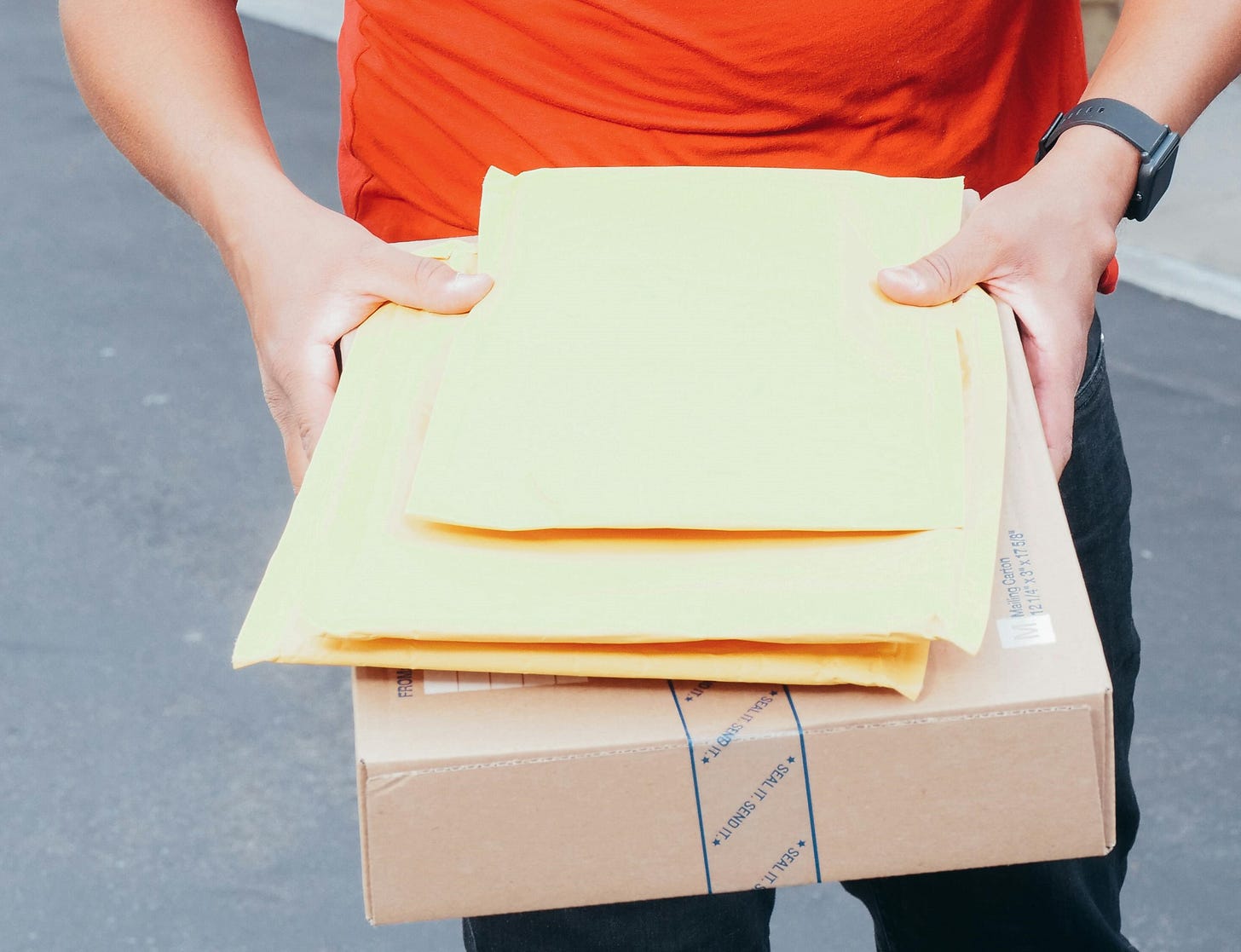 man holding envelopes and package as though to hand them to someone