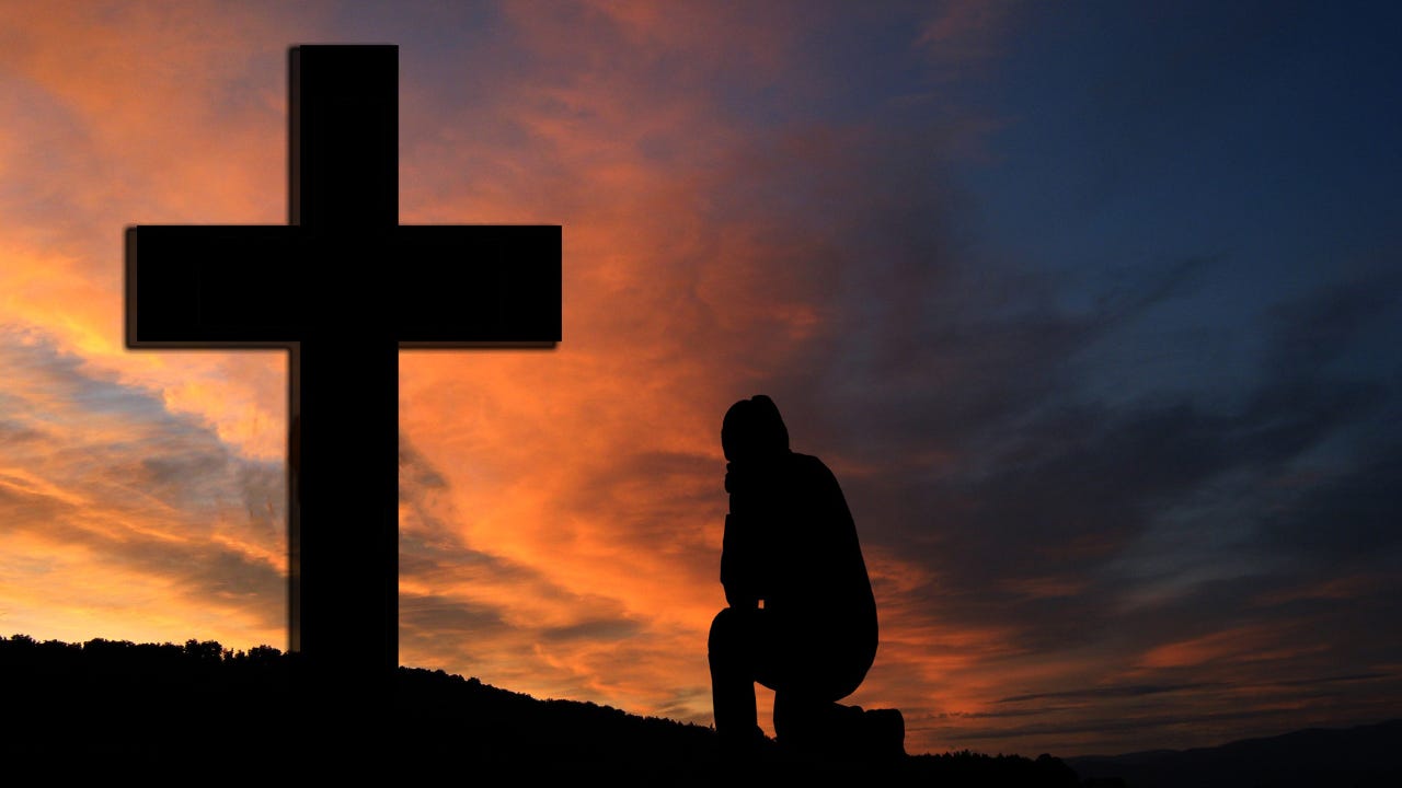 A person kneeling in front of the cross. 