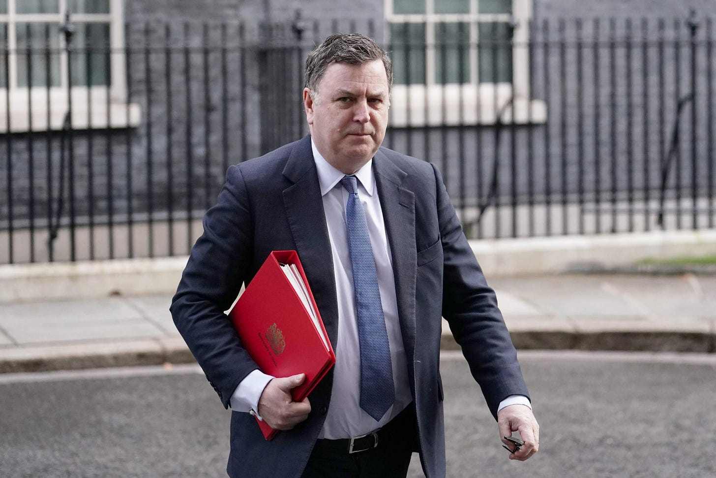 The Work and Pensions secretary Mel Stride is pictured carrying a red book and looking glum