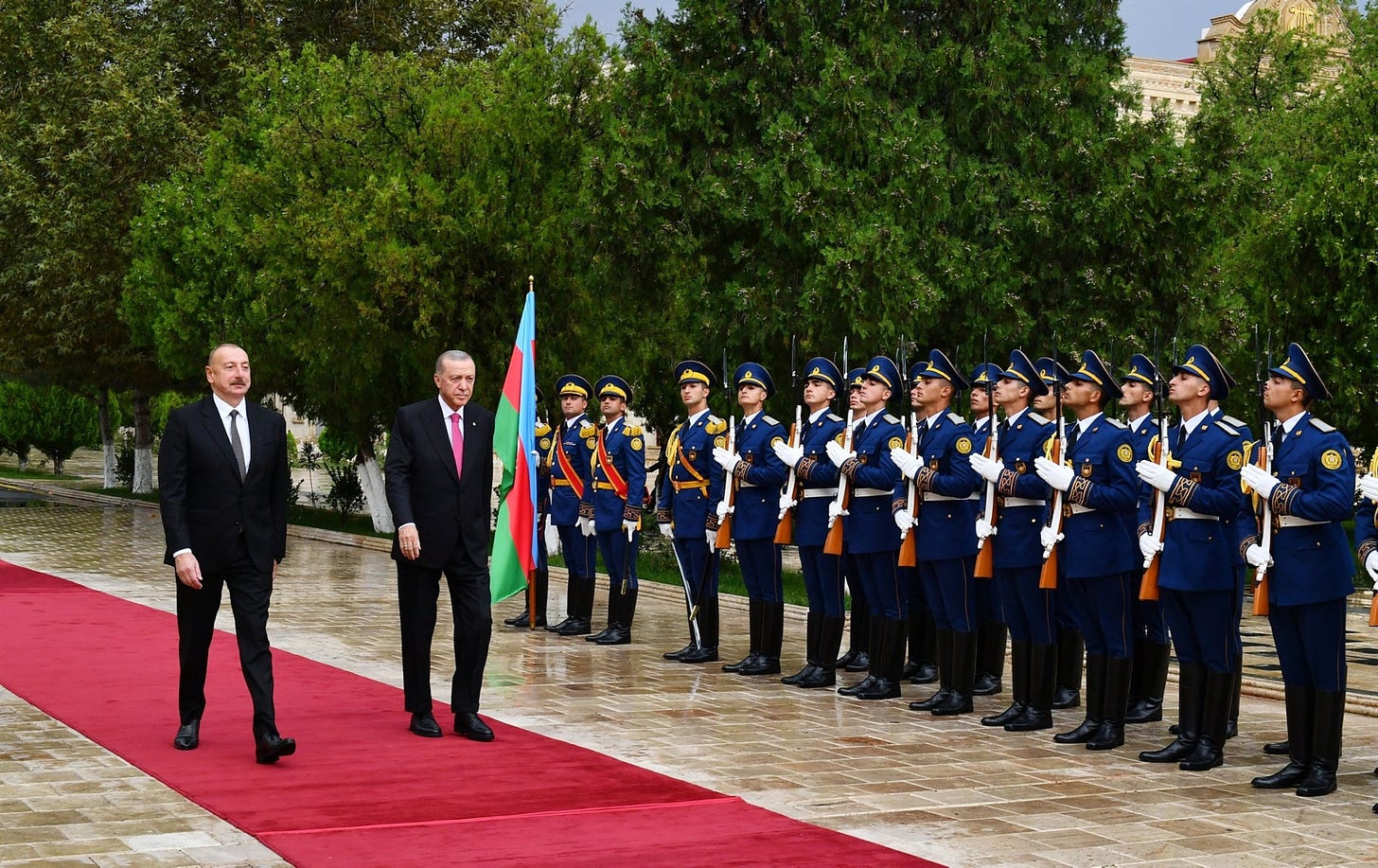 A person standing on a red carpet with a person in a suit and tie

Description automatically generated