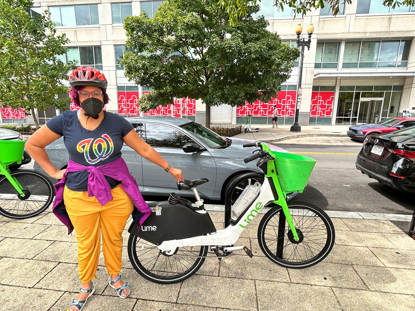 Kristen, masked and with a helmet on, standing next to a Lime e-bike outside in Navy Yard DC