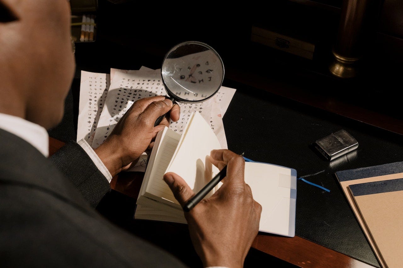 man staring at decoding sheet and writing characters in a notebook