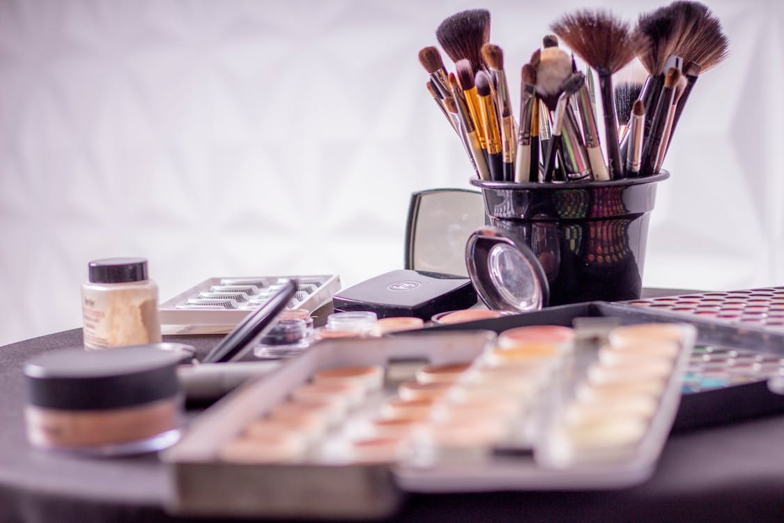 Free Close-up of a professional makeup brush set and cosmetics on a table for beauty use. Stock Photo