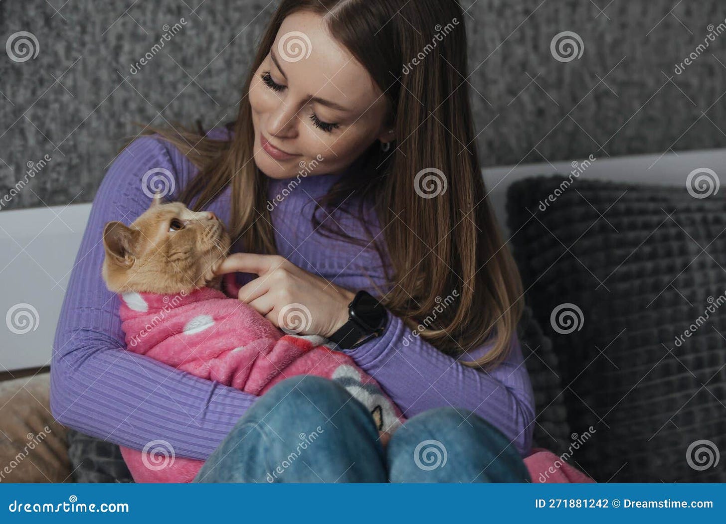 Cute domestic cat wrapped in a baby blanket in the arms of a young woman