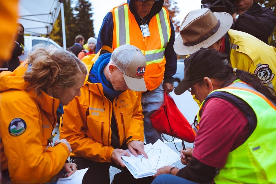 A group of civil defense team members gathered around a map, planning a search area as part of their emergency preparedness efforts.