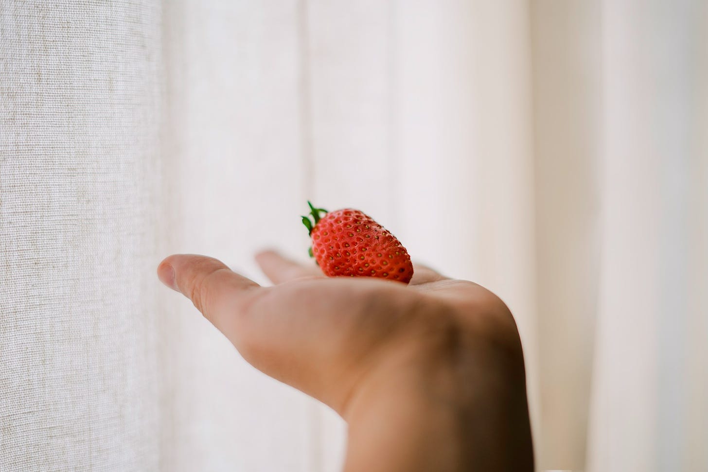 A strawberry on an outstretched palm