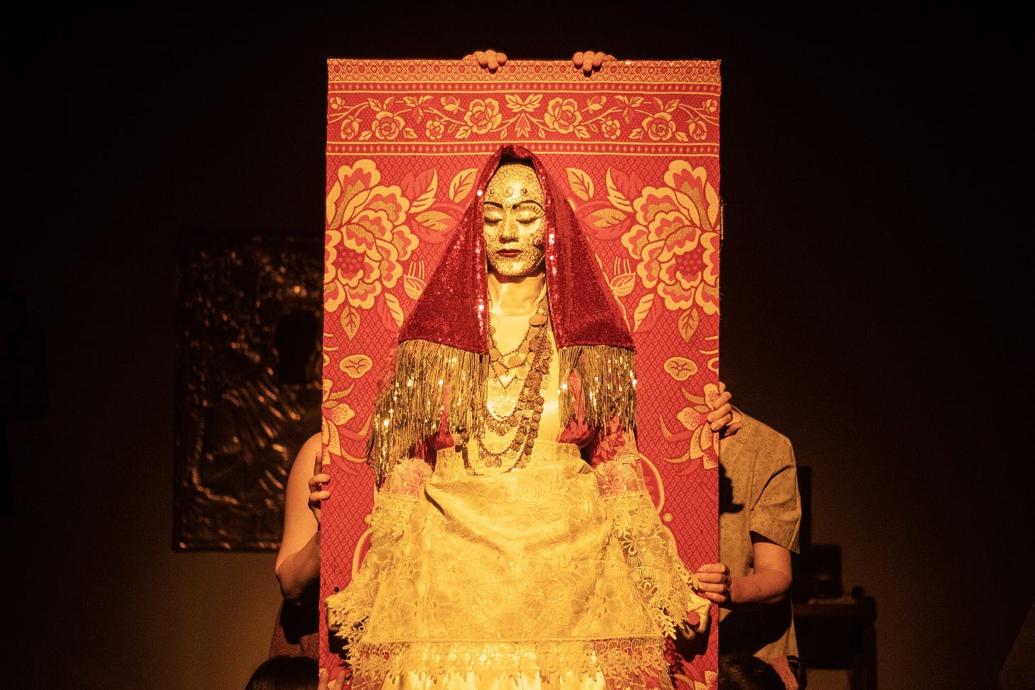 A woman in a gold mask wearing traditional Balkan dress and a red veil.
