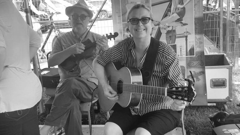 Man and woman musician playing in a festival workshop setting.