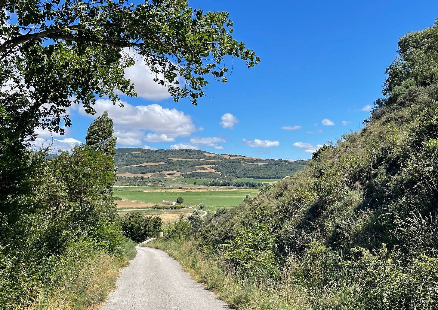 A footpath leads from the green hills down to a fertile plain.