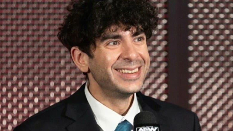 AEW President Tony Khan sits behind a microphone at a press conference.