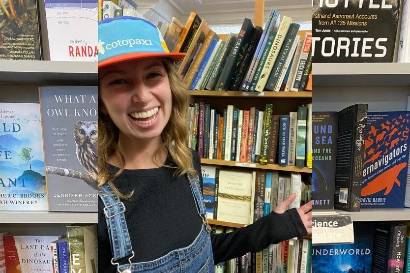 Haley, a blonde woman in a blue and orange hat, smiles in a bookstore aisle