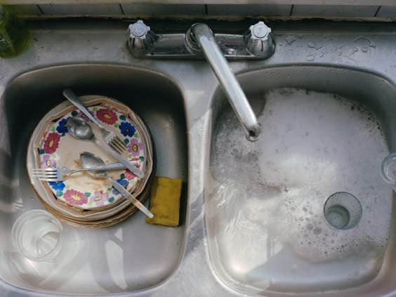 This may contain: a dirty sink with dishes and utensils in it