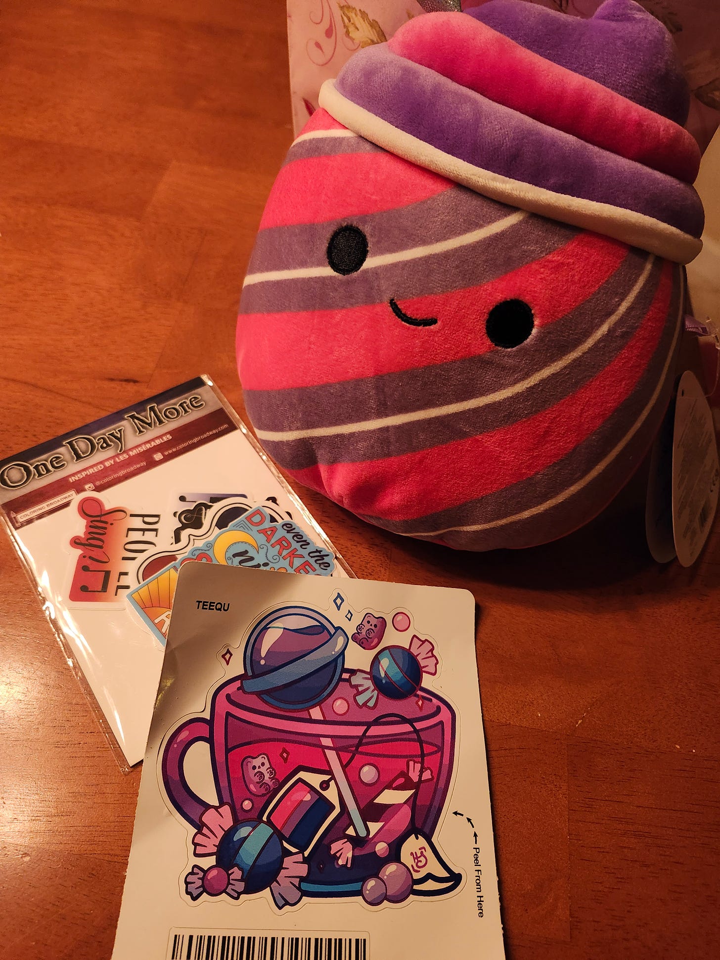 A mini bisexual slushie squishmallow and various Les Mis and bisexual stickers