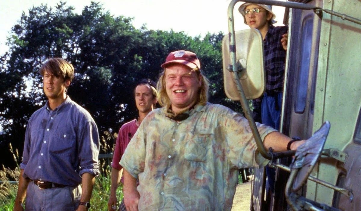 Stil from Twister: scintists (Alan Ruck, sean Whalen, Philip Seymour Hoffman, and possibly Jeremy Davies?) stand next to a white panel truck in a field with some trees in the background.