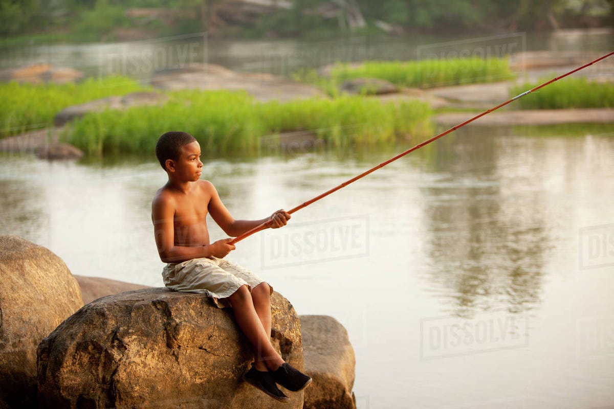 African American boy fishing in lake - Stock Photo - Dissolve