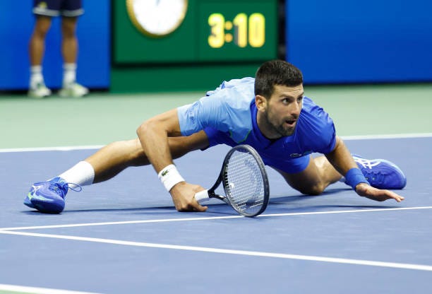 Serbia's Novak Djokovic watches his shot while falling on the court as he plays Russia's Daniil Medvedev in the US Open tennis tournament men's...
