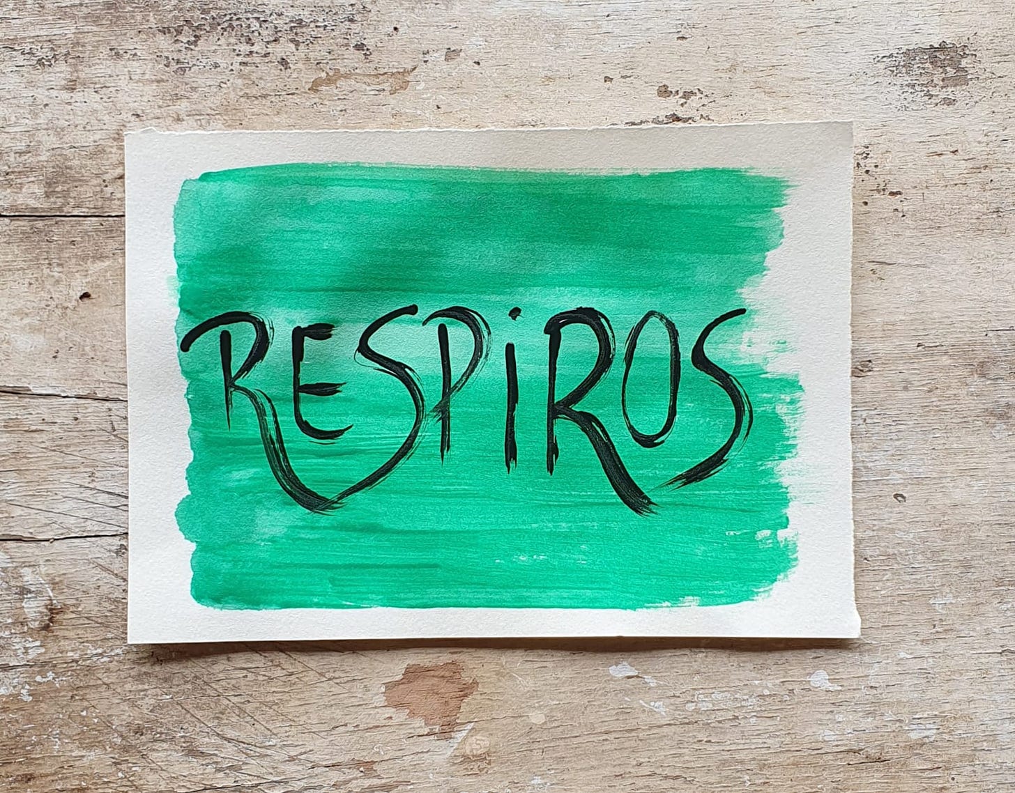 Fotografia de um papel pintado de verde sobre um fundo de madera com o escrito "Respiros"