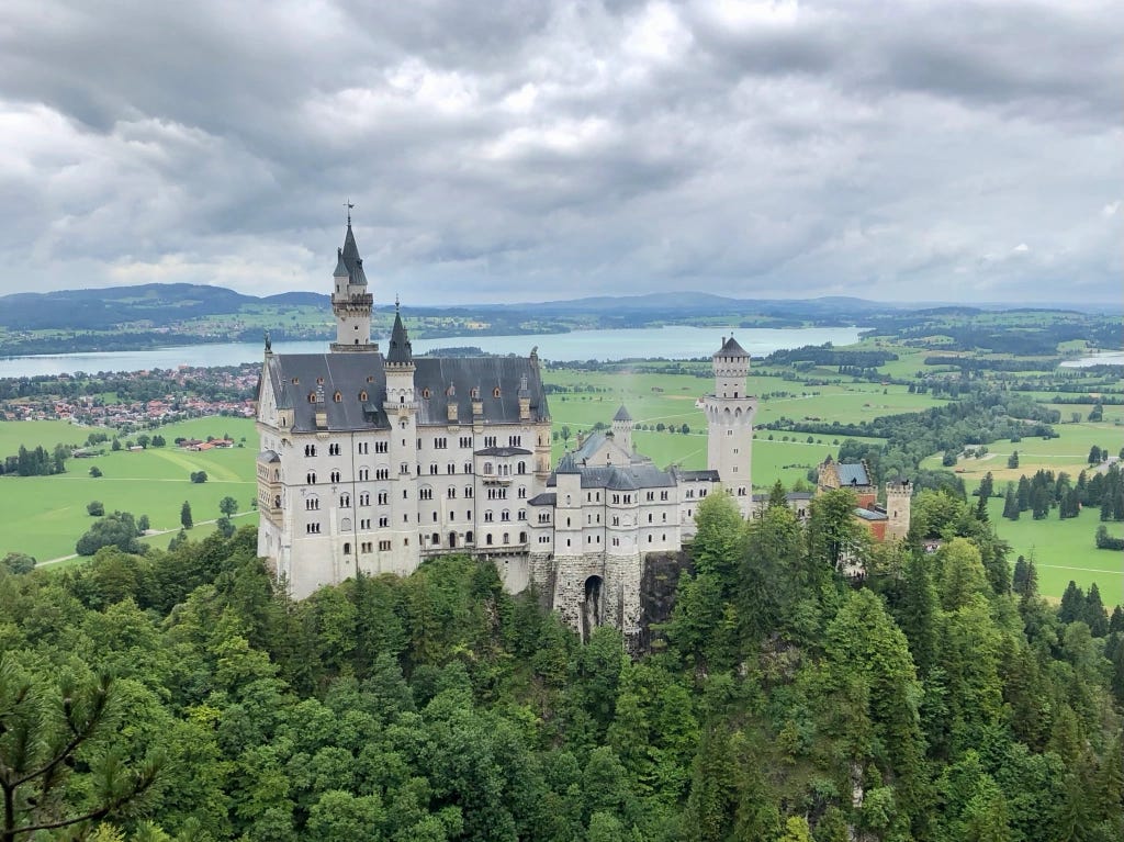 Neuschwanstein Castle with green fields and a lake in the background